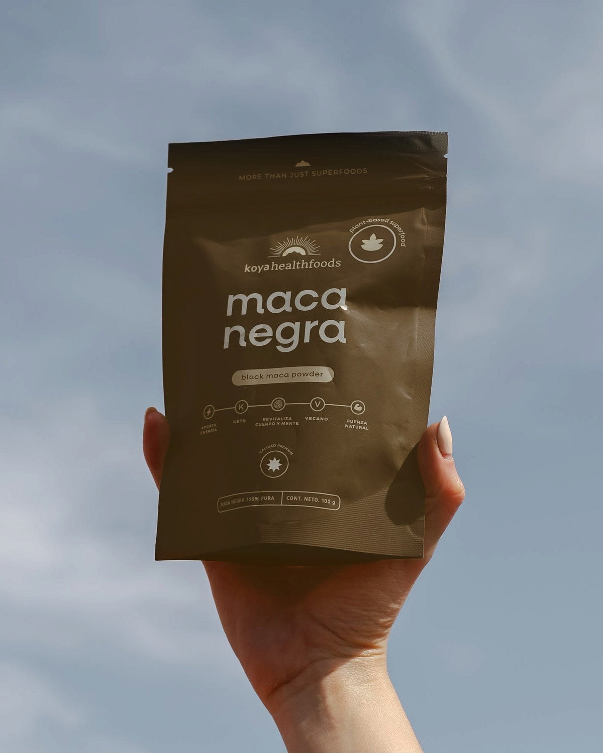 Mano sosteniendo la bolsa de Maca Negra Koya contra el cielo